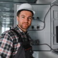 Electrician wearing safety helmet working on an electrical panel in a building under construction